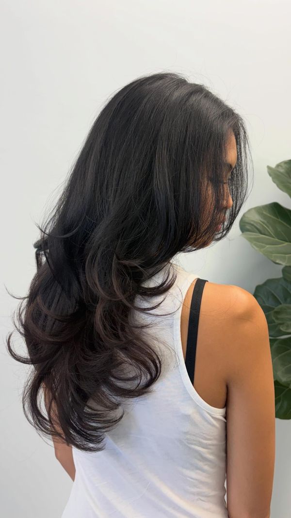 Long layered cut on dark hair with a smooth blowout